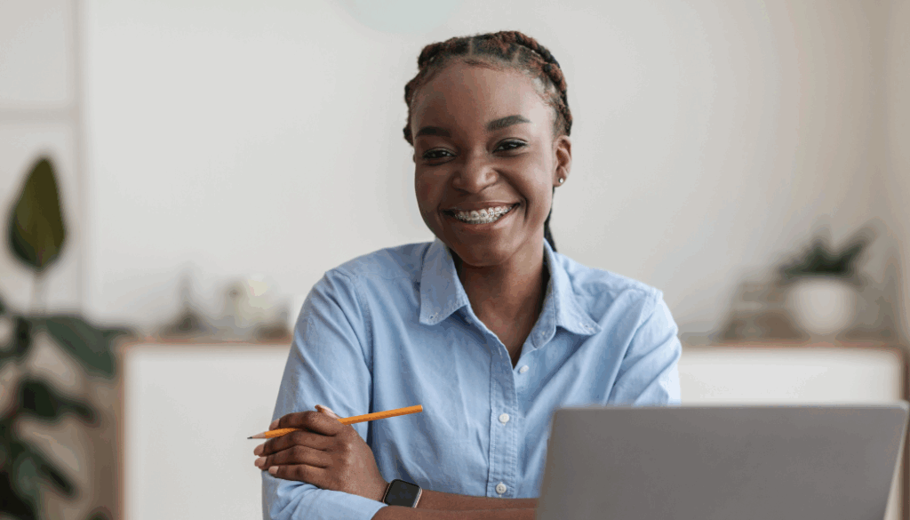 femme souriante devant son ordinateur qui regarde face caméra